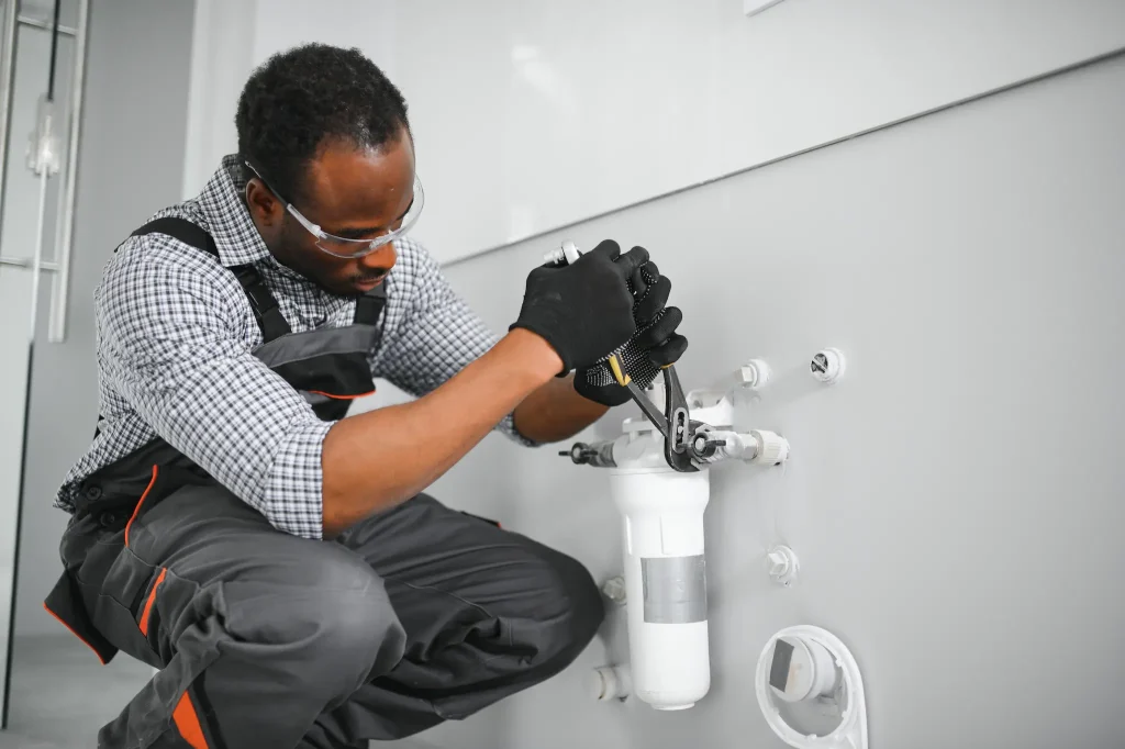 A plumber installing a white water treatment system with a wrench.