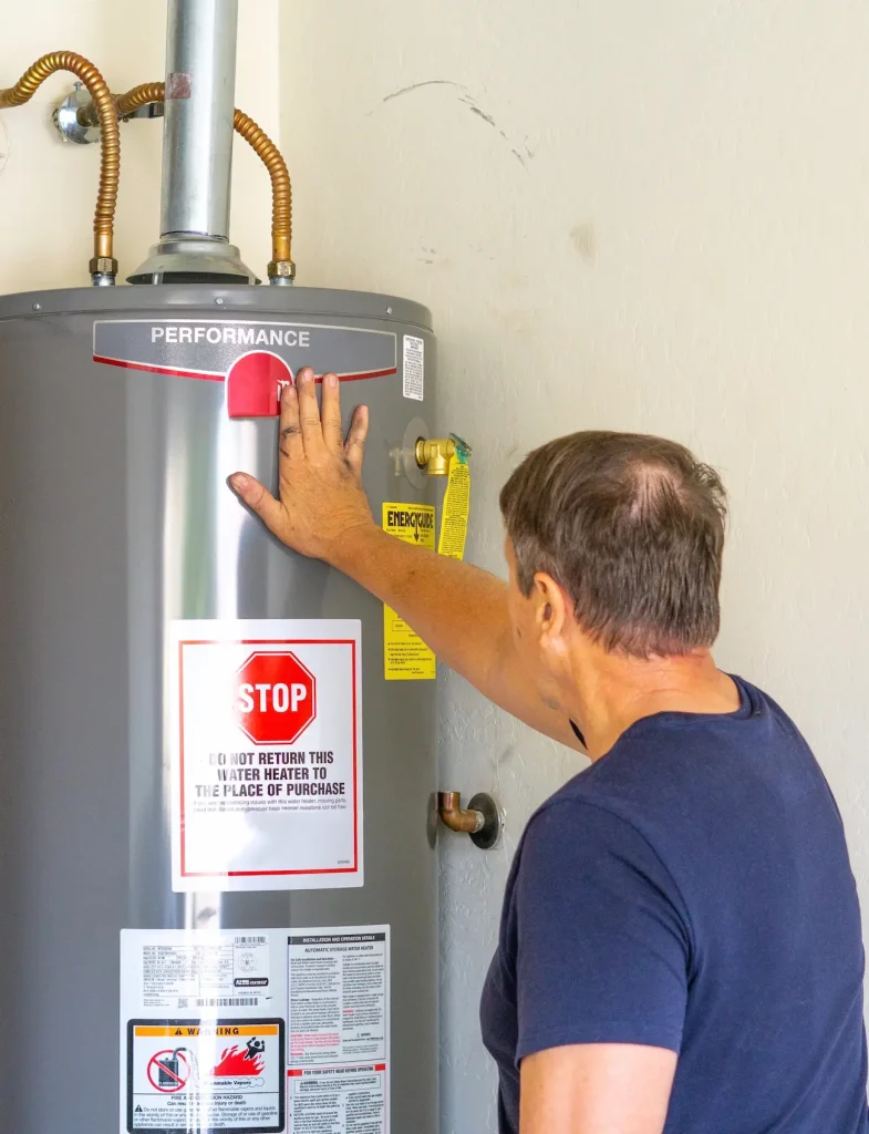 A plumber inspects a silver Performance water heater.