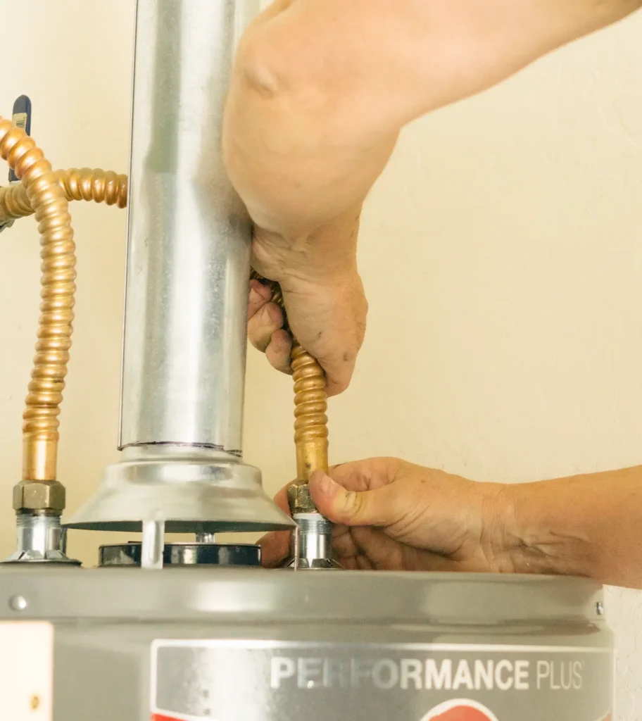 A plumber connecting a water heater to the gas line.