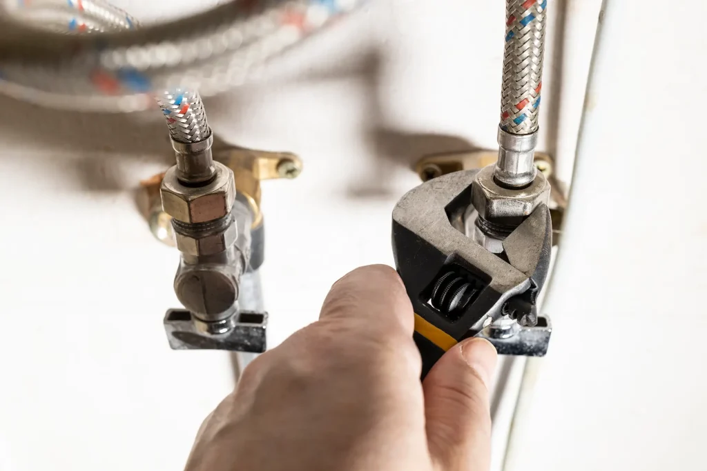 A plumber’s hand using a wrench to fix a gas line connection.